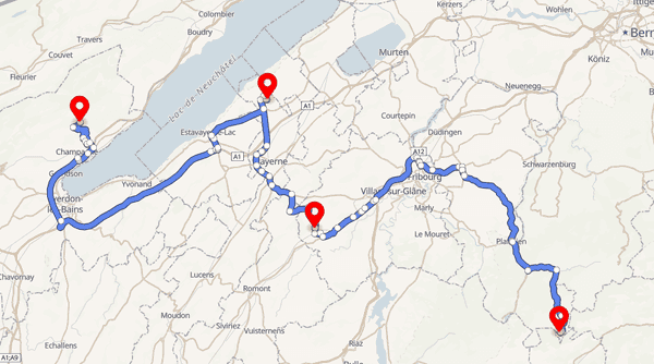 Route example: a blue multi-stop route with red markers and instruction points between Lake Neuchâtel and Fribourg on a MapLibre GL map